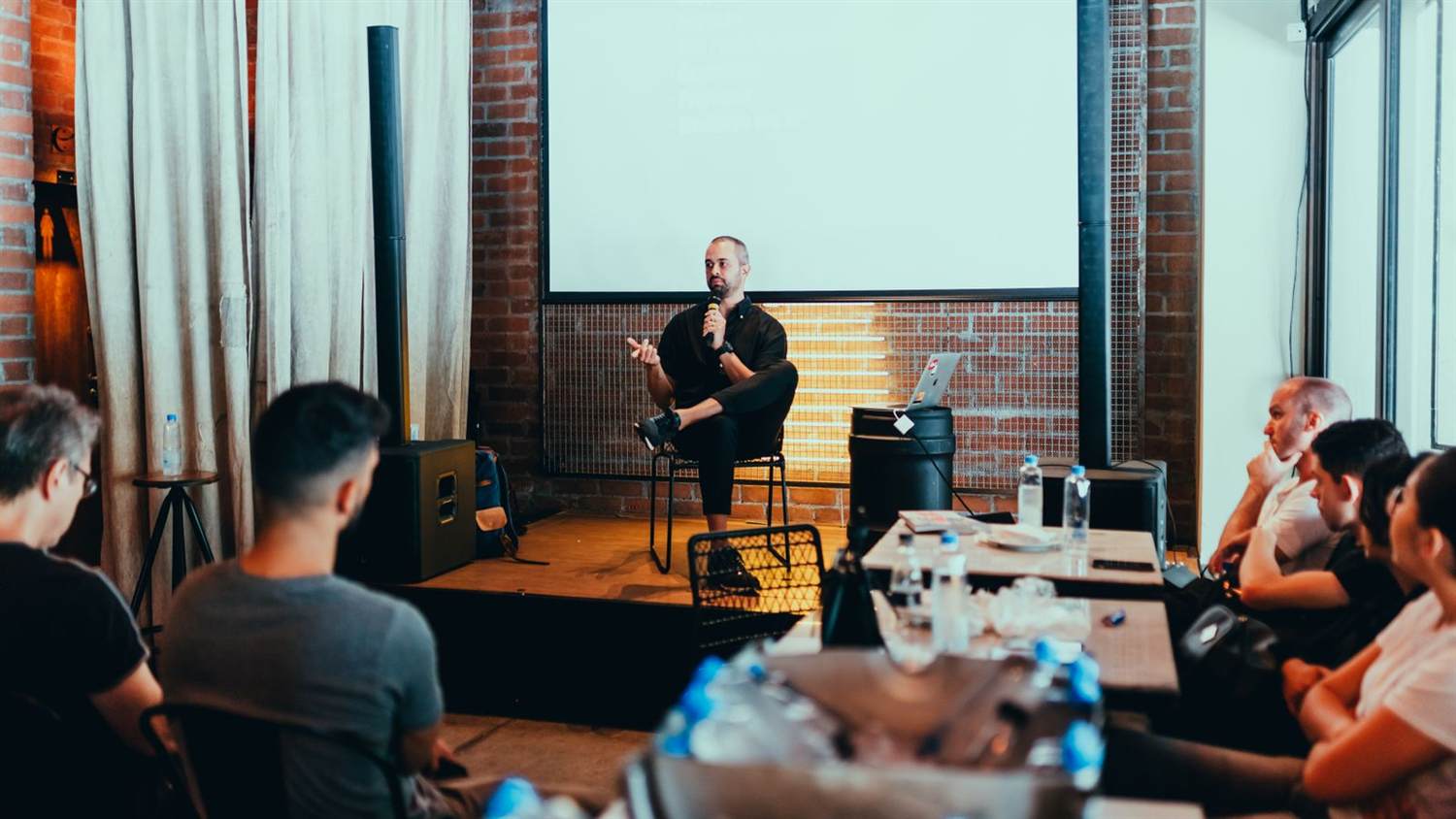 A speaker with a microphone addressing a small breakout audience