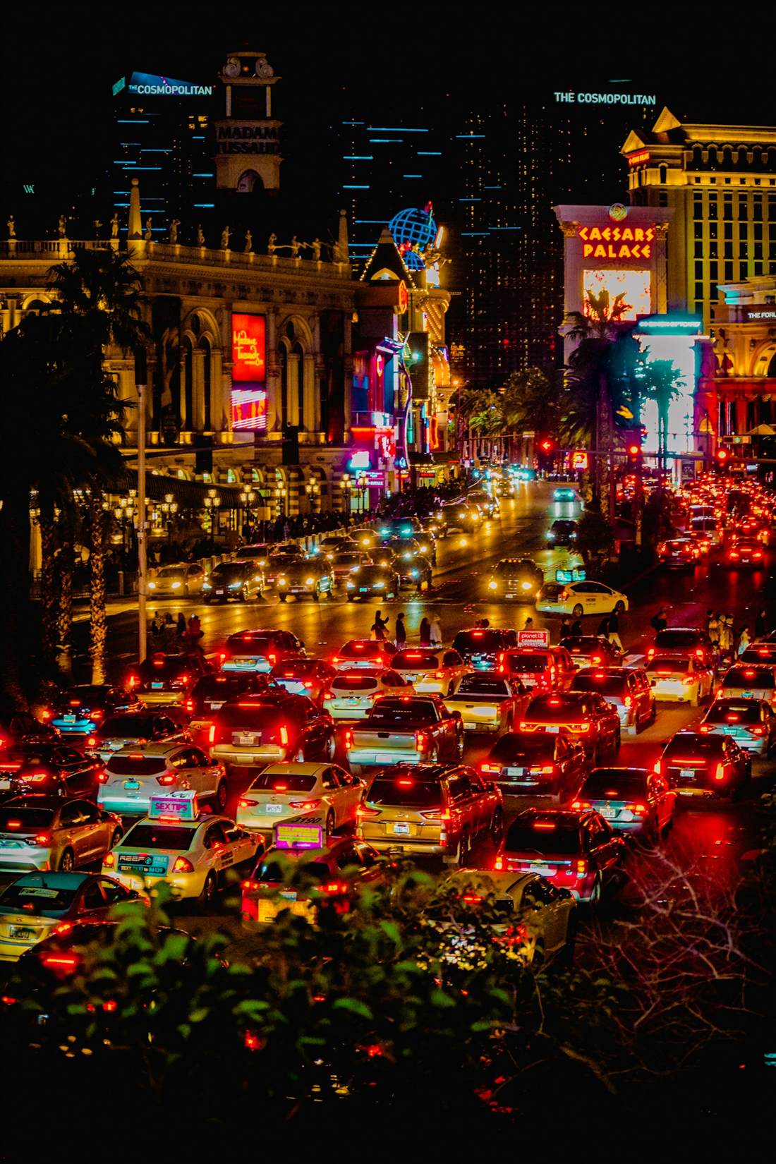 Night traffic on Las Vegas Boulevard with the Caesars Palace sign and the Venetian's Madame Tussauds tower