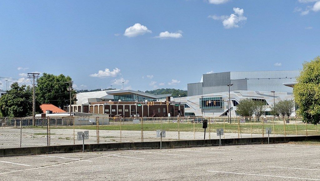 The renovated Charleston Coliseum & Convention Center seen across a parking lot from Virginia Street, its angular silver and glass front beside the older brick wing