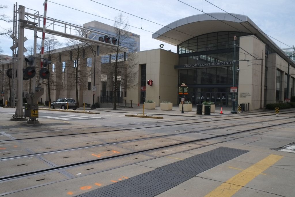 The glass and stone College Street entrance of the Charlotte Convention Center, with light rail tracks in the foreground