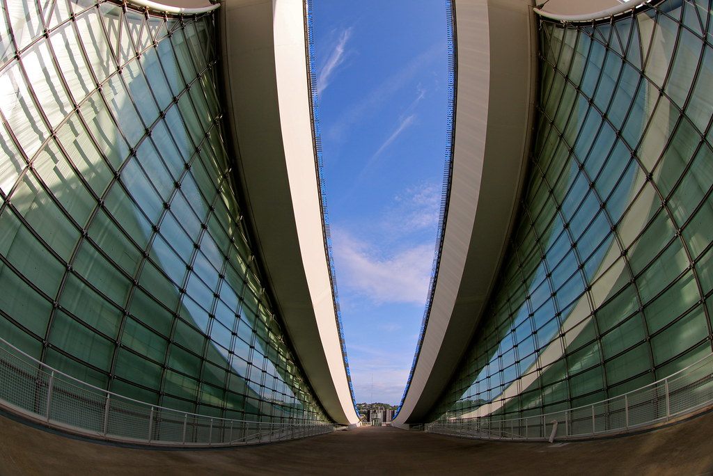 Curved glass walls of the David L. Lawrence Convention Center framing a walkway under blue sky