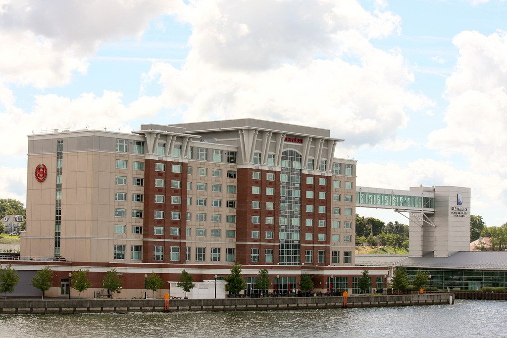 The Sheraton tower on the edge of Presque Isle Bay, joined by a glass sky bridge to the Bayfront Convention Center's tower and glass-walled hall on the right