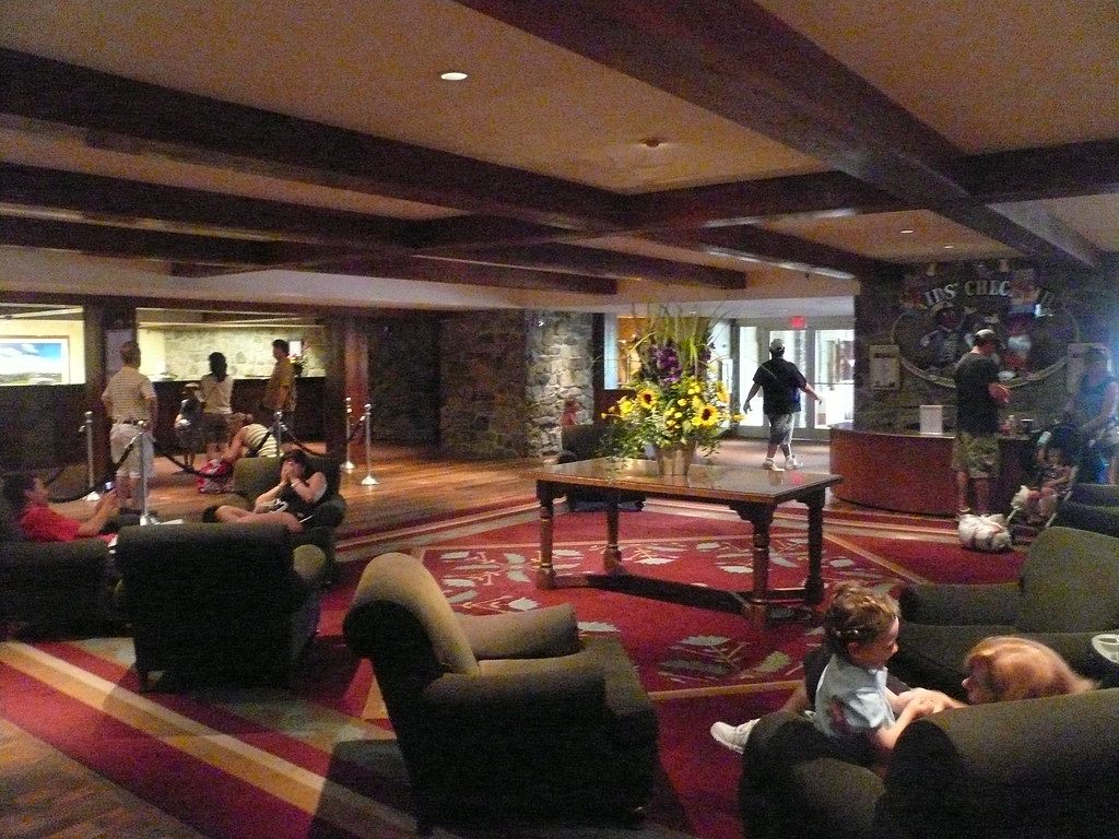 Guests on leather armchairs in the Hershey Lodge main lobby, with timber ceiling beams, stone walls and the check-in desk behind