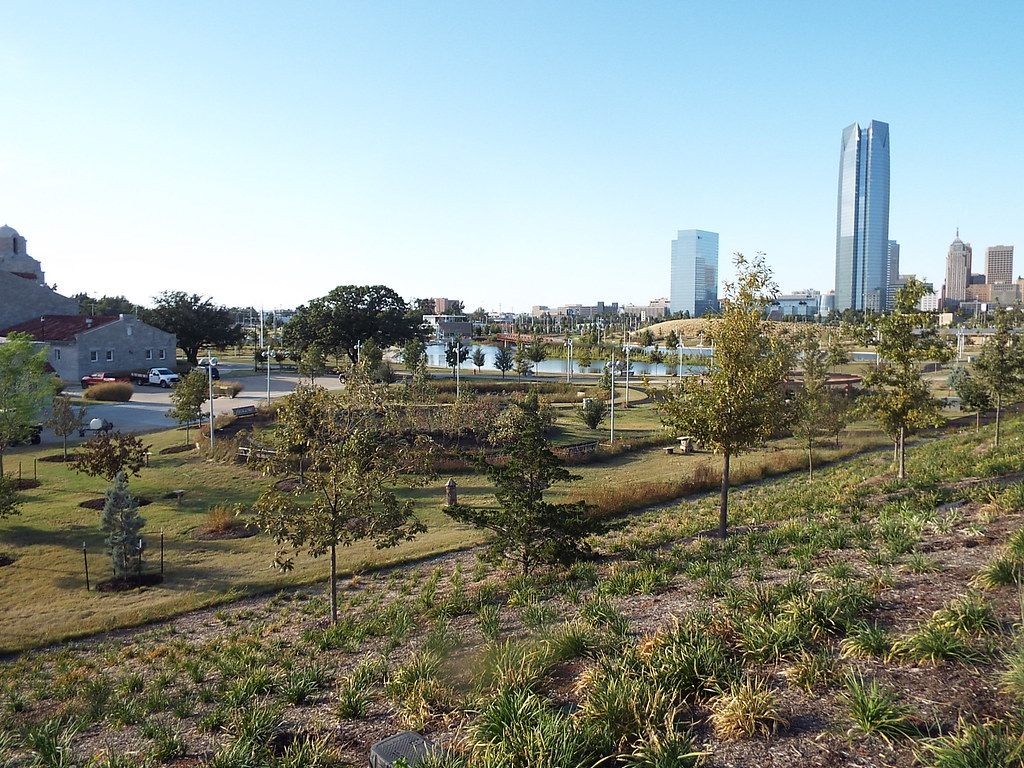 Young trees and a pond in Scissortail Park, with Devon Tower and the downtown Oklahoma City skyline beyond