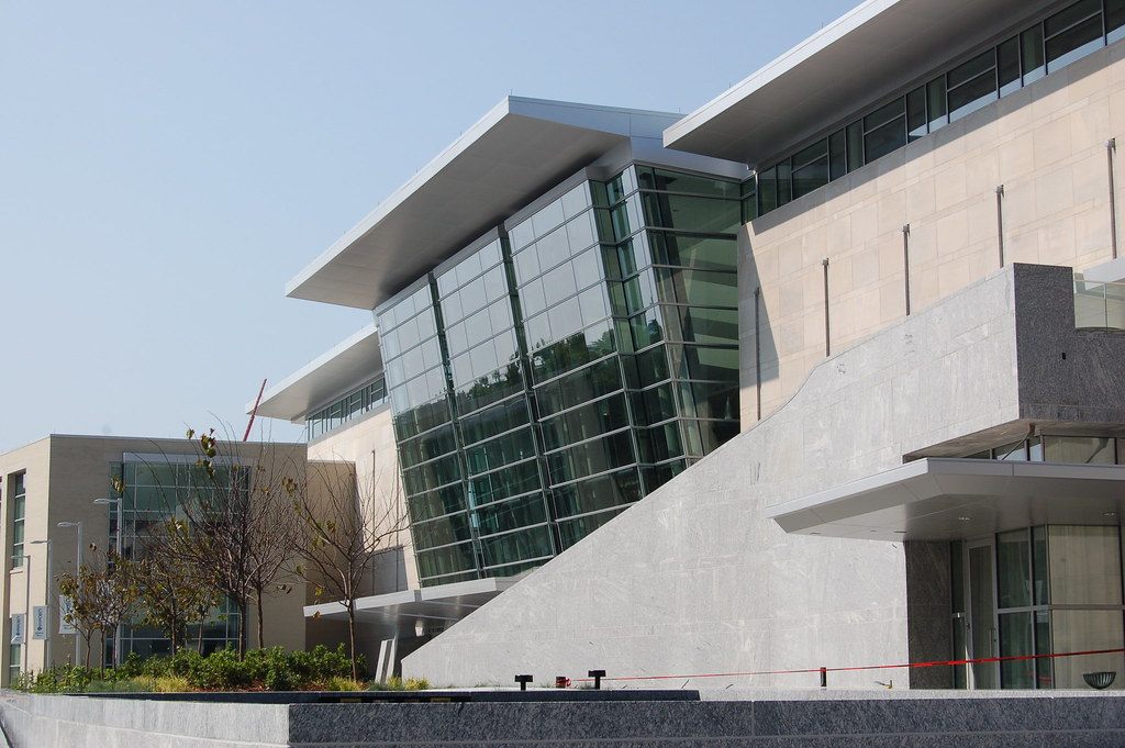 The glass and limestone facade of the Raleigh Convention Center, now the Atlantic Union Bank Convention Center, with its wide cantilevered roof edges against a clear sky