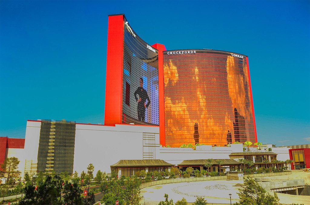 The red-edged Hilton tower and the copper-glass Crockfords and Conrad tower of Resorts World Las Vegas above the low-rise resort podium