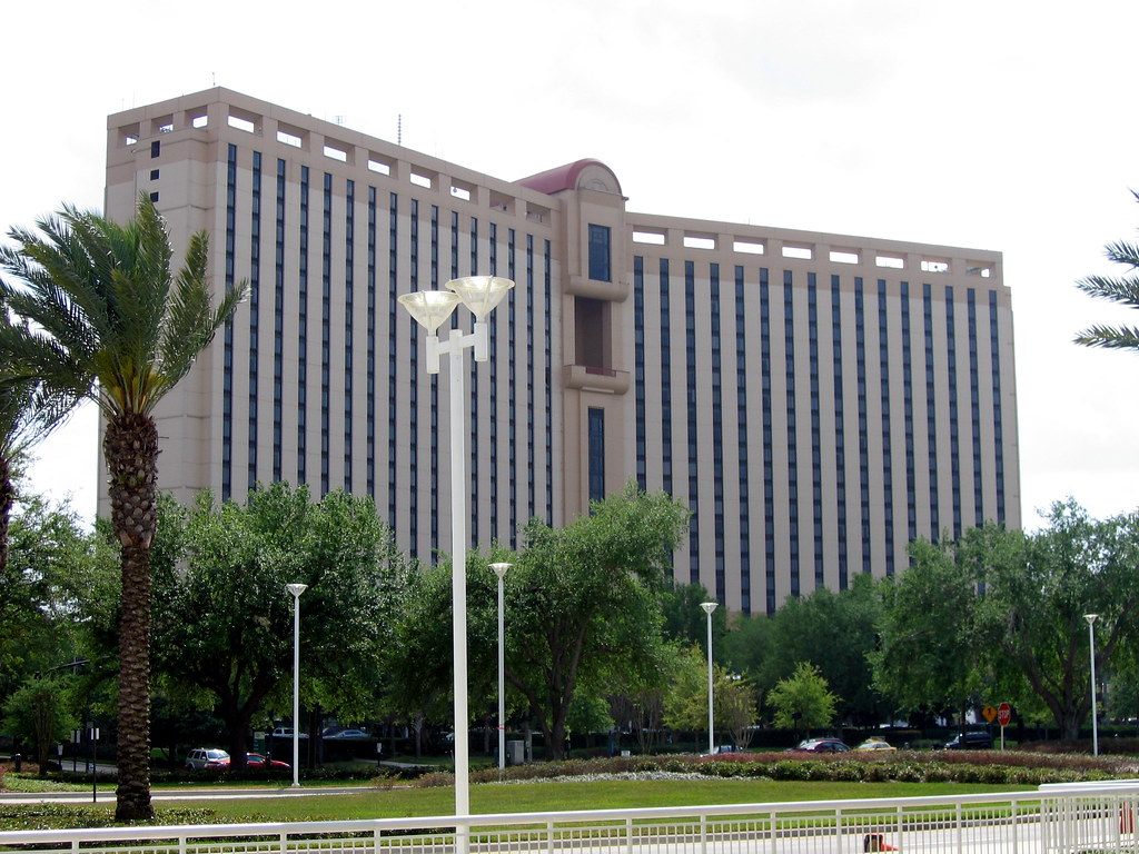 The tall beige Rosen Centre Hotel tower with its long rows of windows, behind palm trees, lawns and street lights
