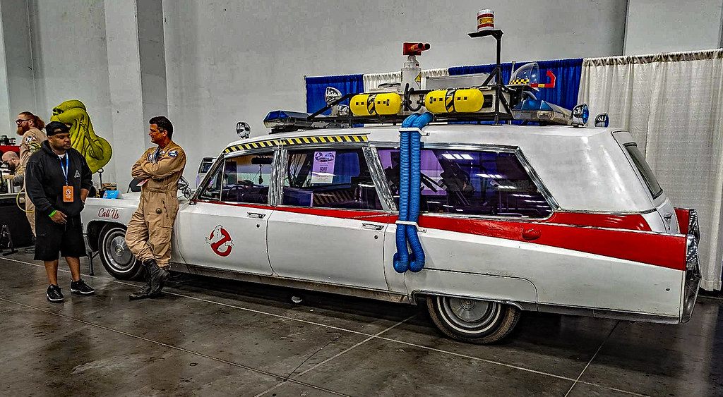 A replica Ghostbusters Ecto-1 ambulance and fans in costume on the exhibit hall floor at Tidewater Comicon, Virginia Beach Convention Center