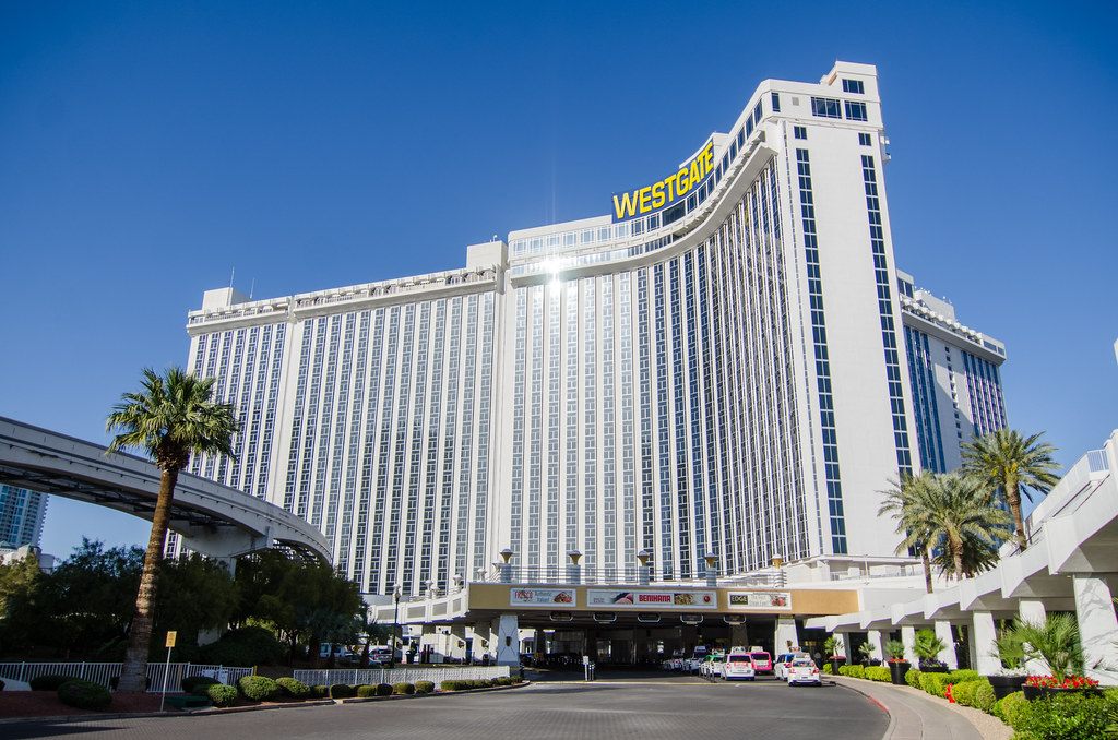 The curved white tower of Westgate Las Vegas Resort & Casino above its main entrance, with the monorail track passing on the left