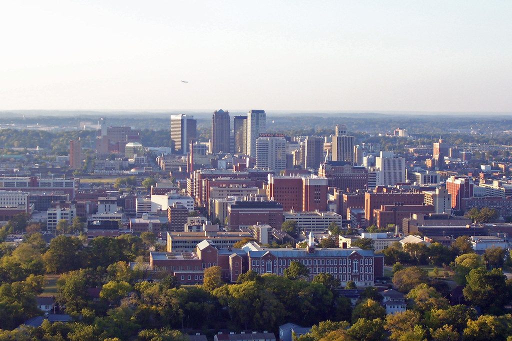 Downtown Birmingham's office towers rising above brick buildings and trees, seen from the Southside
