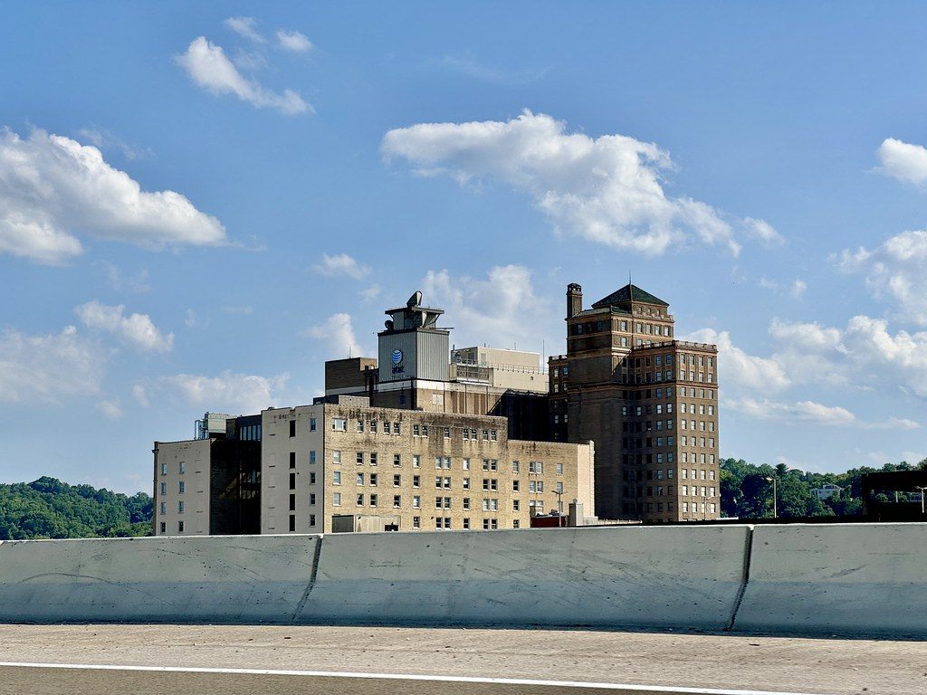 Older brick and stone downtown Charleston buildings with a rooftop tower, seen over a highway barrier