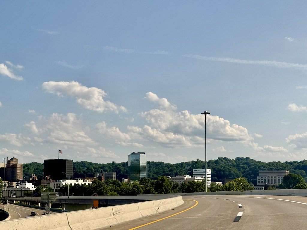 Downtown Charleston's office towers and wooded hills seen from a curving ramp of the West Virginia Turnpike
