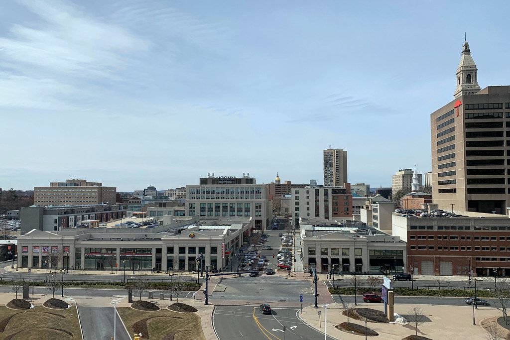 Front Street district buildings and a wide downtown Hartford street seen from above, with the Travelers Tower on the right