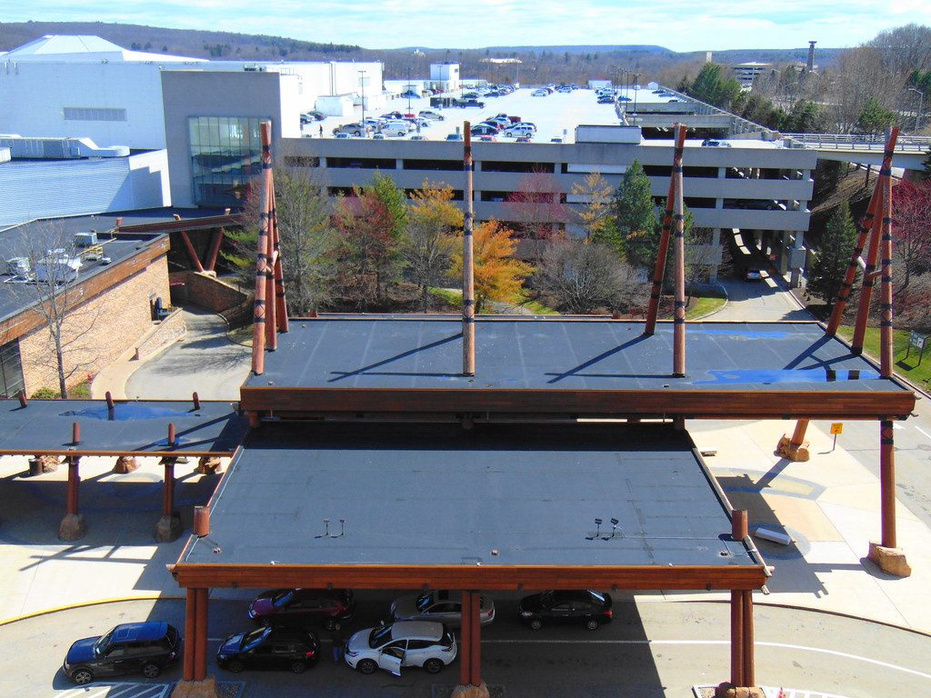 A timber-post entrance canopy at Mohegan Sun seen from above, with a parking garage behind