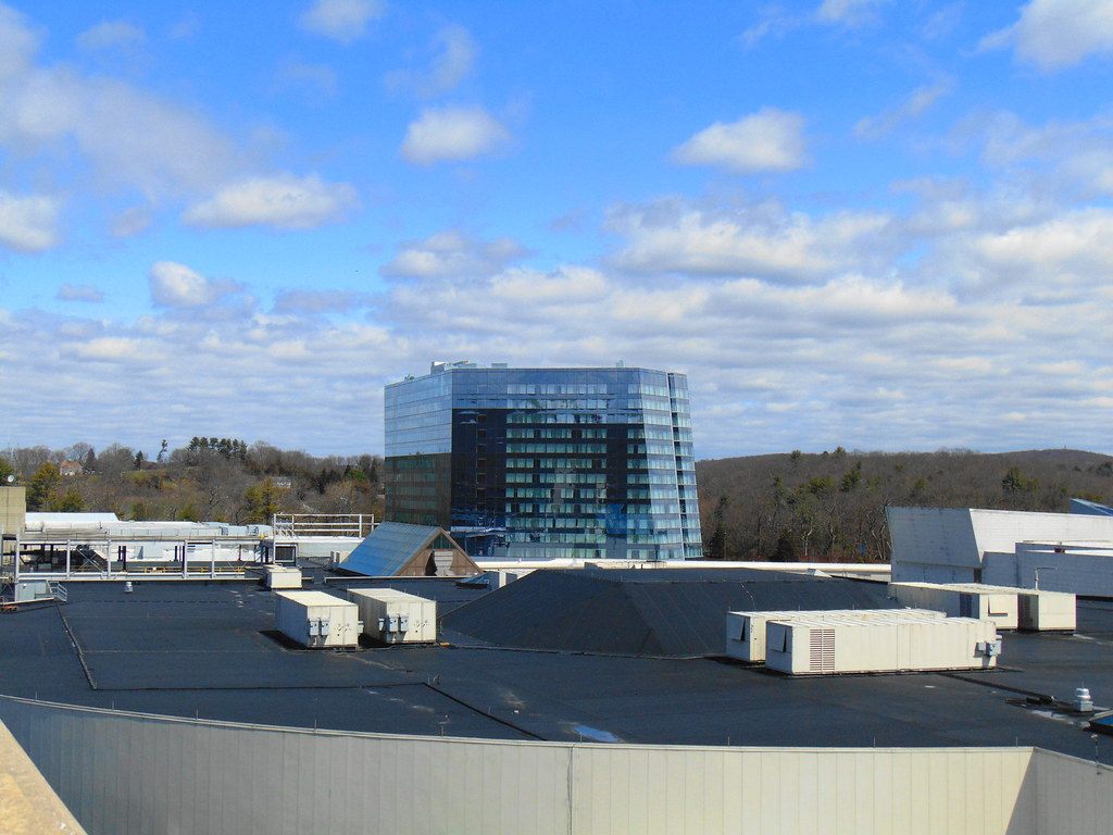 The glass Earth Tower hotel rising behind the flat roofs of Mohegan Sun, with wooded hills beyond