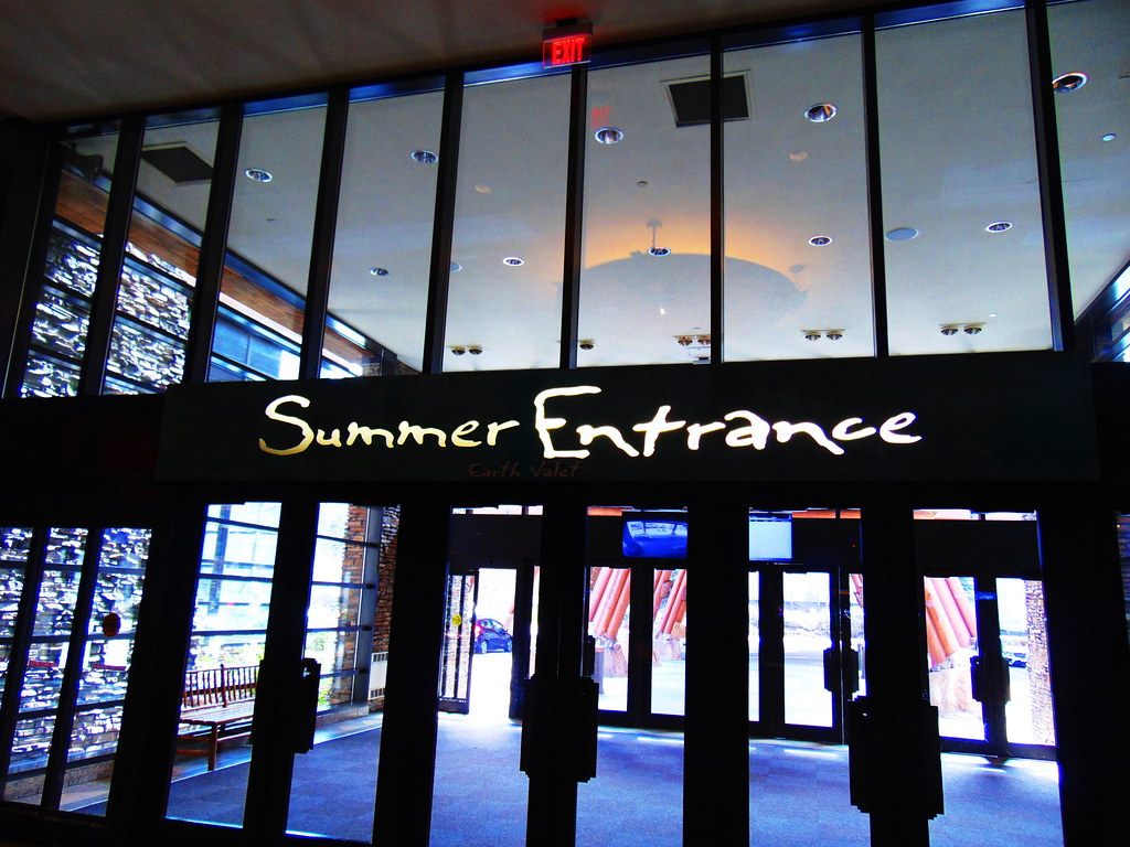The lit Summer Entrance sign above glass doors at Mohegan Sun's Earth valet entrance