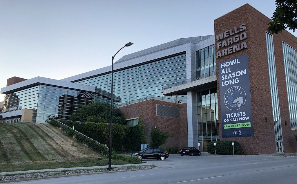The glass and brick exterior of Wells Fargo Arena with its name in large letters on a brick tower and a team banner hanging below