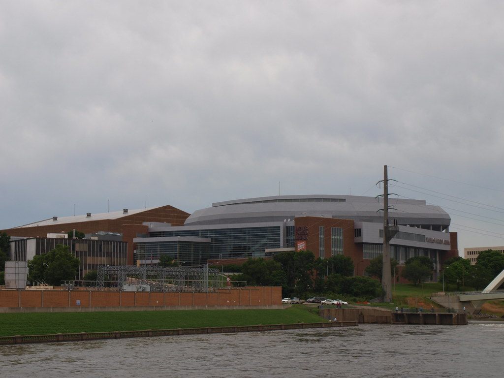 The Iowa Events Center seen across the Des Moines River: the brick exhibit hall at left and the curved silver roof and glass front of the arena at right