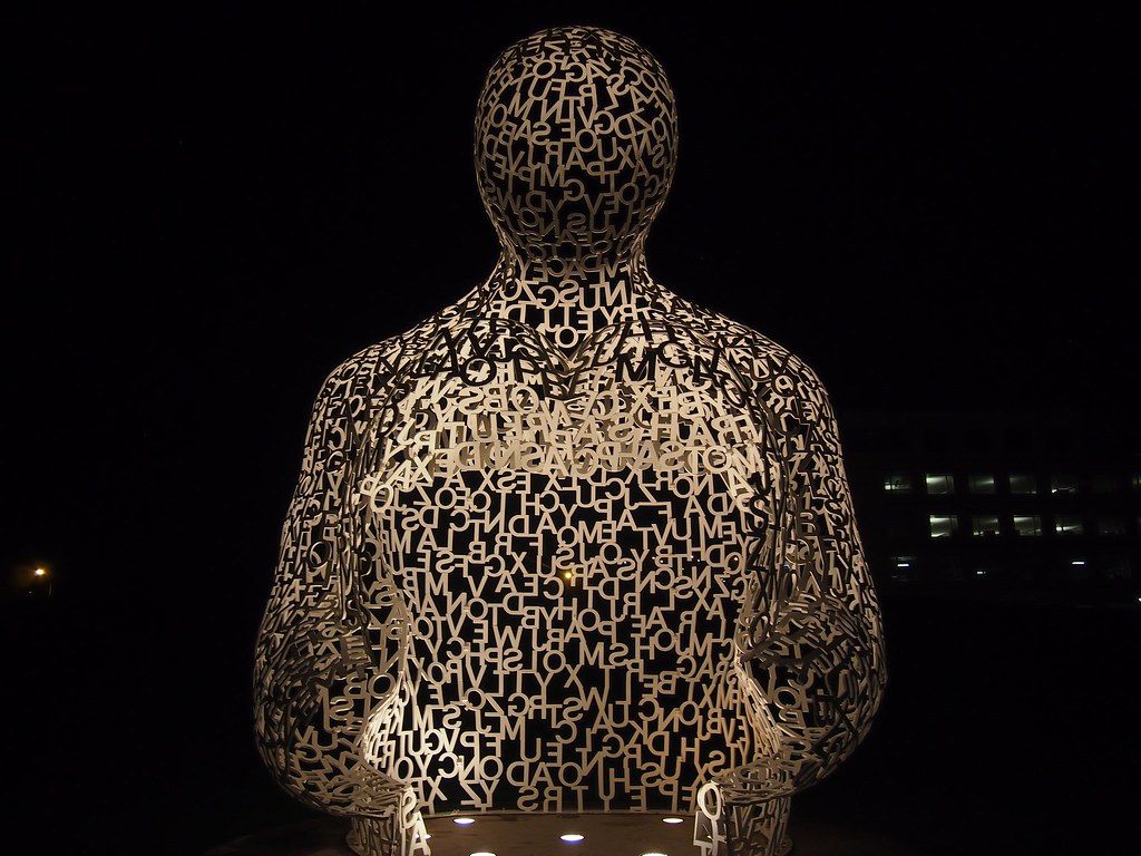 The white lattice of letters forming the seated Nomade sculpture, lit at night in the Pappajohn Sculpture Park