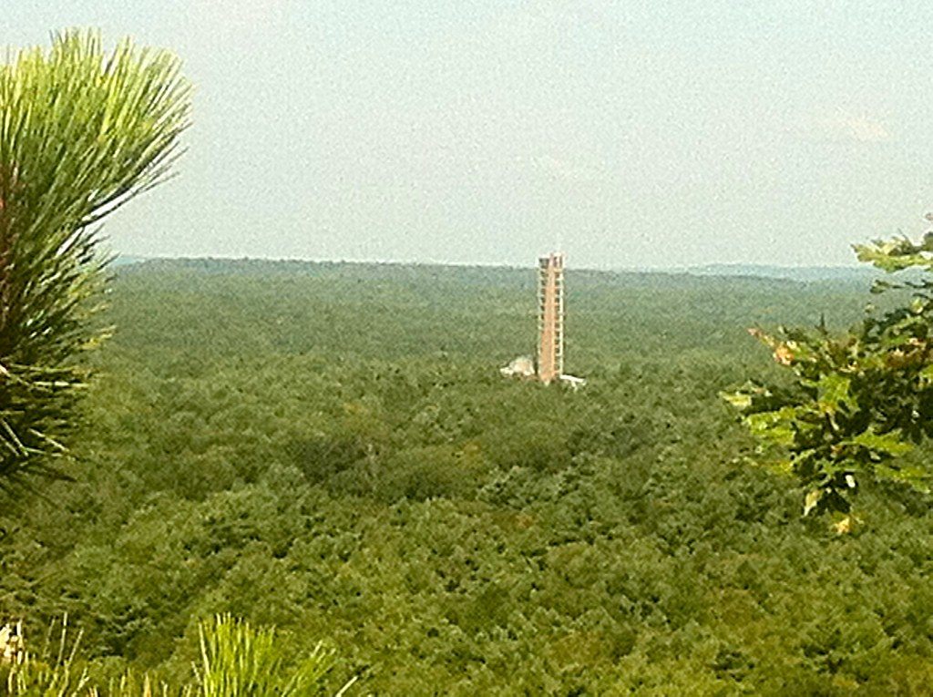 The stone and glass tower of the Mashantucket Pequot Museum rising above an unbroken forest canopy
