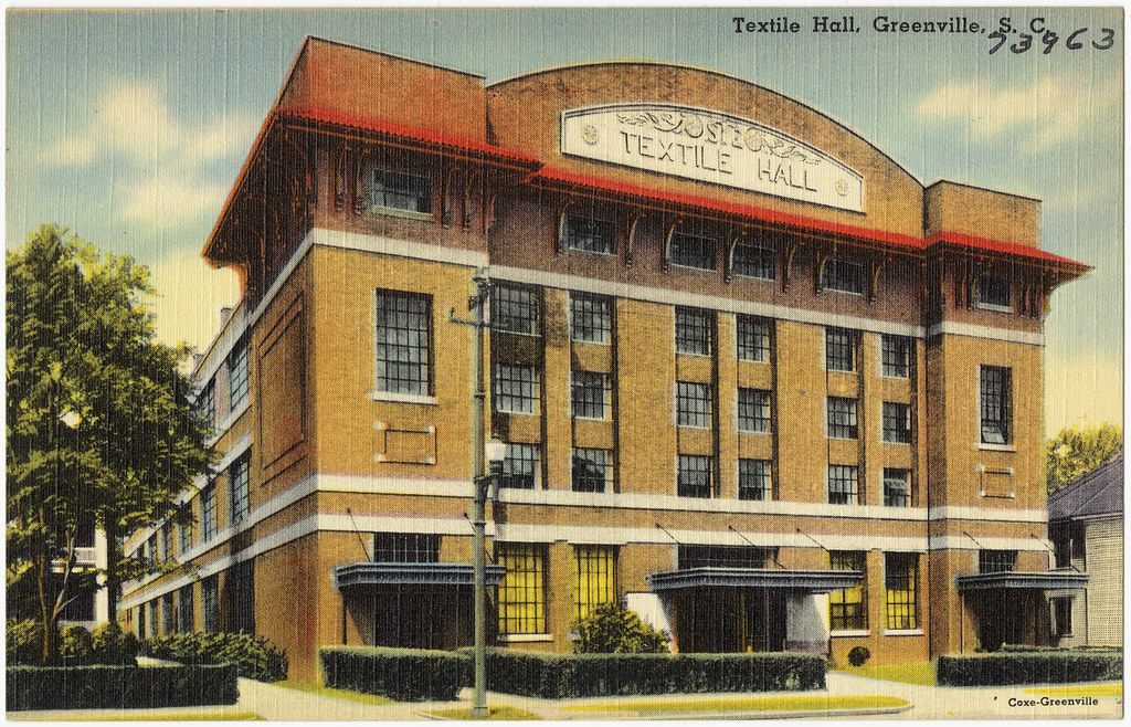 Vintage postcard of the original Textile Hall in Greenville, a four-story brick building with a curved parapet reading Textile Hall