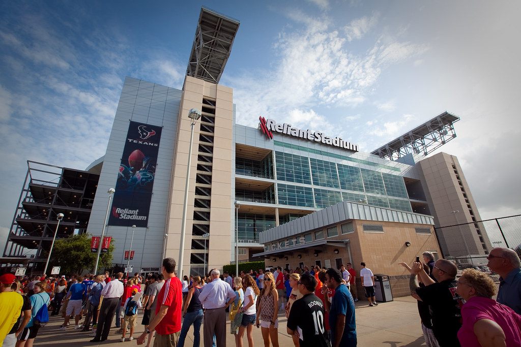 A crowd gathers outside the stadium in Reliant Park under its Reliant Stadium sign on a sunny event day