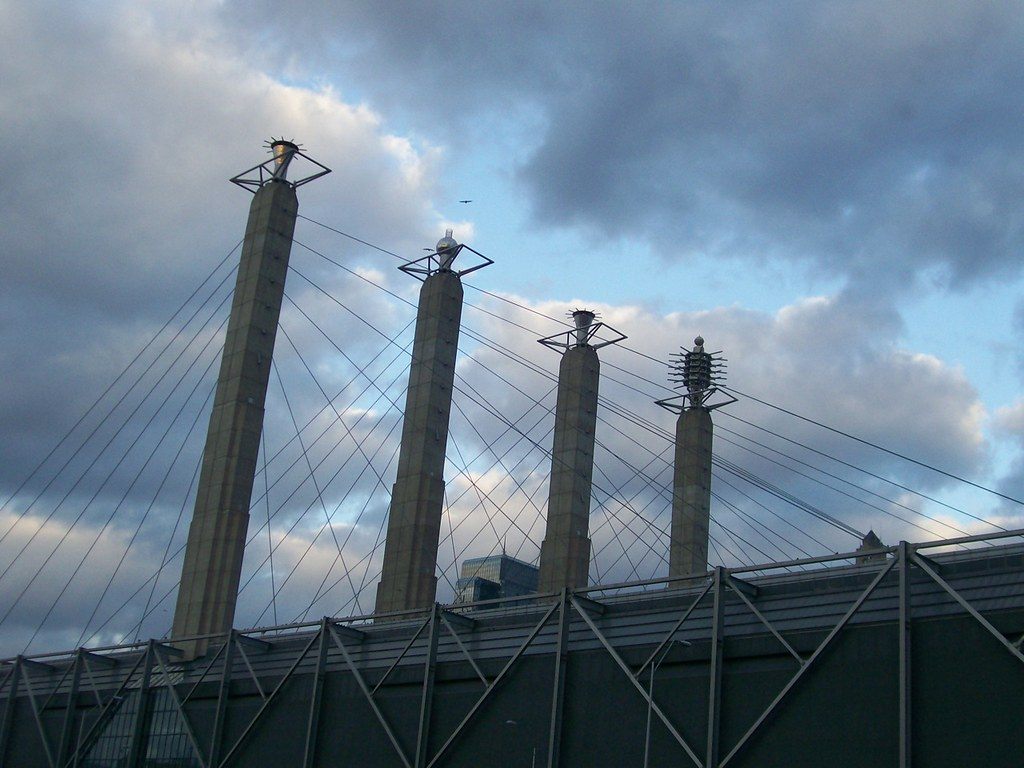 The four concrete Bartle Hall pylons with their Sky Station sculptures and fanning roof cables against a cloudy sky
