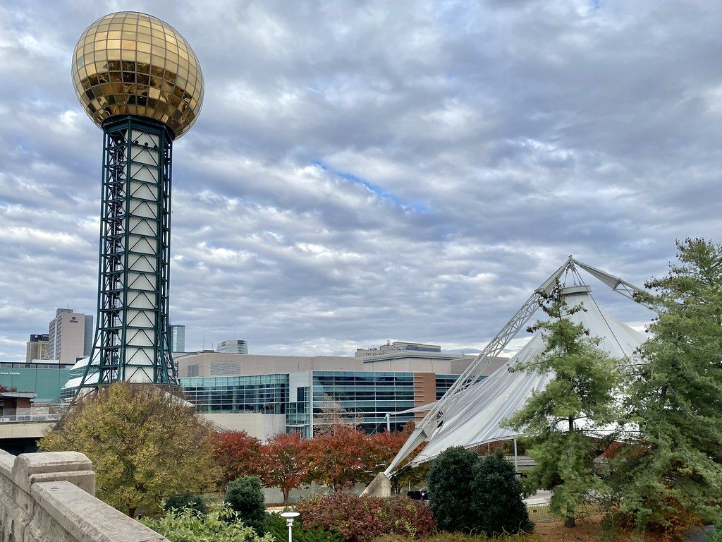 The gold-glass Sunsphere and the white canopy of the Tennessee Amphitheater in World's Fair Park, with downtown Knoxville buildings behind