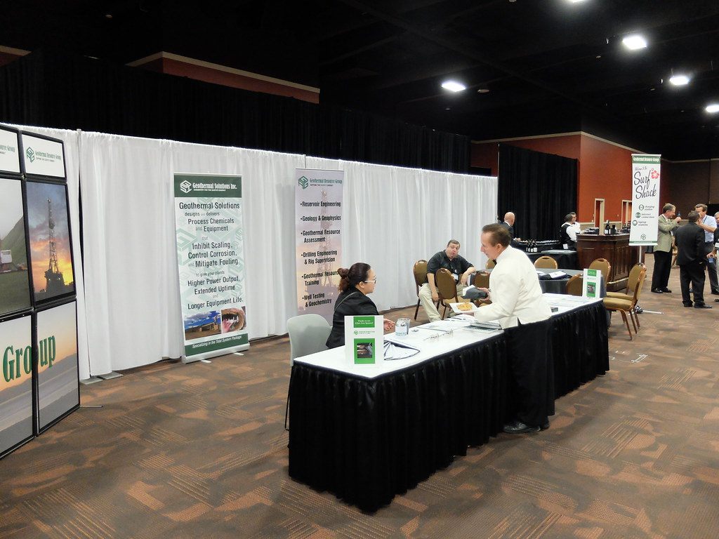 A tabletop exhibit with pipe-and-drape walls and banner stands on a patterned carpet, under a dark ceiling with spotlights, at MGM Grand