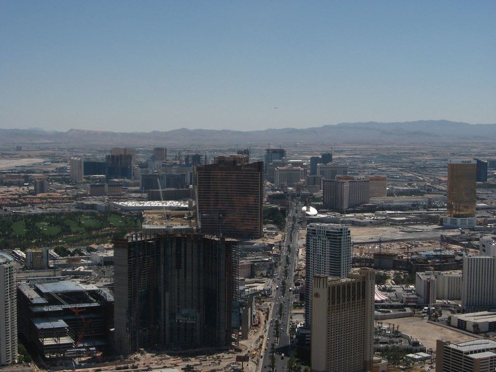 The north end of the Las Vegas Strip seen from high above, with towers under construction in the foreground and the desert and mountains beyond