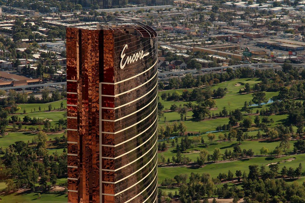 The bronze Encore tower rising beside the green fairways of the Wynn Golf Club, seen from above