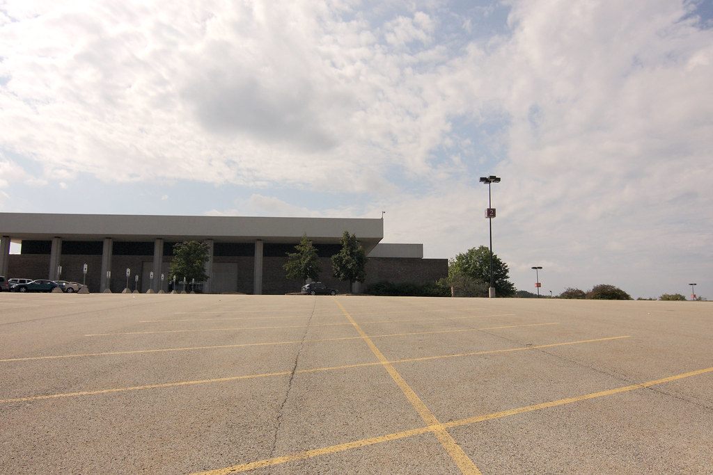 Monroeville Mall's low exterior across a wide empty parking lot, the mall across the road from the Monroeville Convention Center