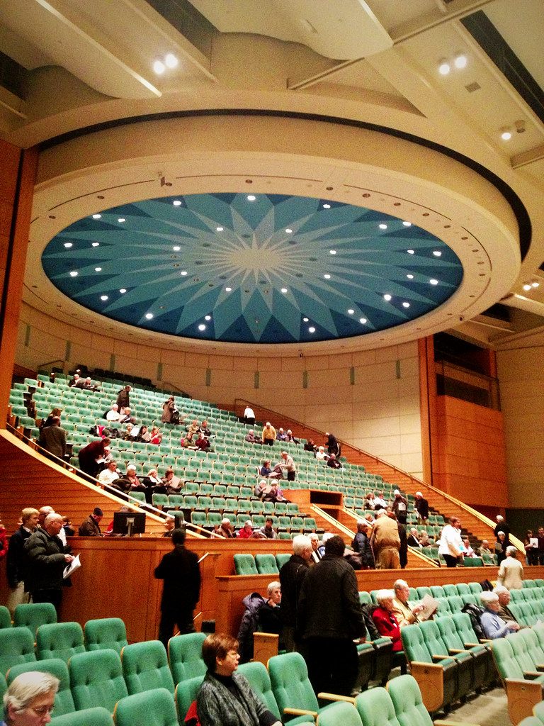 Tiered green seats in the Minneapolis Convention Center auditorium under a round blue starburst ceiling