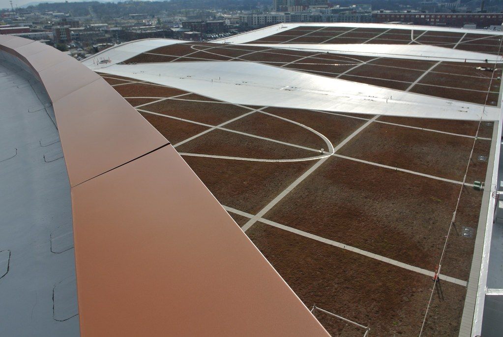 Planted sections of the Music City Center green roof, divided by white walkways, with the copper-colored roof edge in the foreground