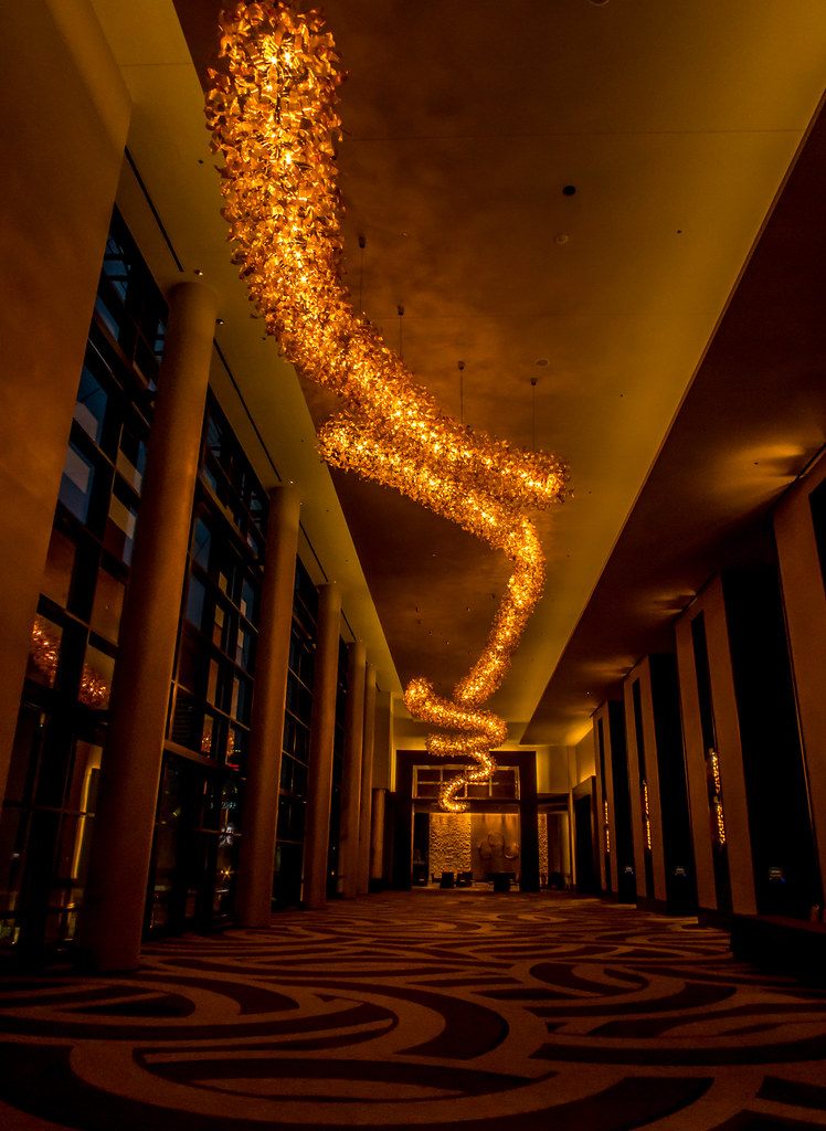 A long carpeted meeting-level corridor at the Omni Nashville Hotel with a spiraling amber chandelier