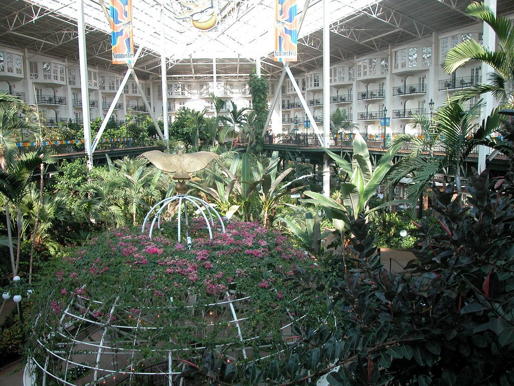 Palms and a flowering dome under the glass and steel roof of a Gaylord Opryland atrium, with balconied guest rooms all around