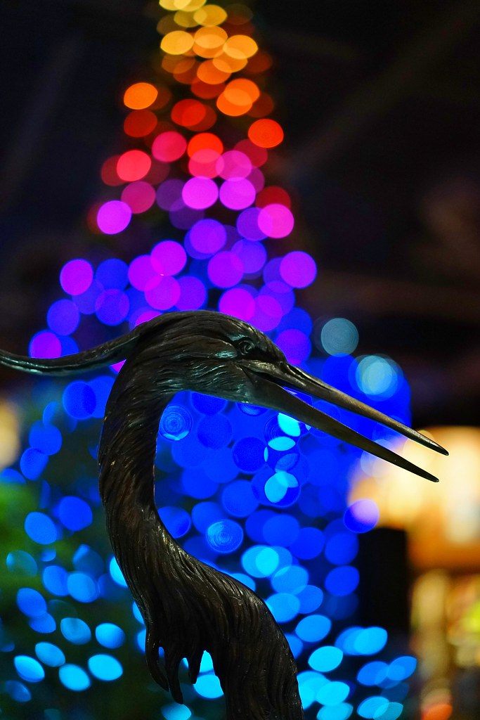A bronze heron sculpture in front of out-of-focus purple, blue and orange holiday lights inside Kalahari Resorts in the Poconos