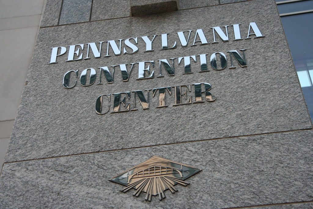 Polished Pennsylvania Convention Center lettering on a granite wall, with the center's train-shed emblem below