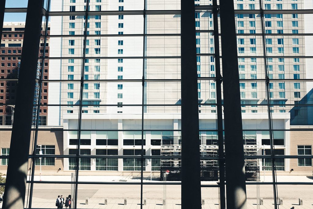 View through the convention center's tall lobby windows toward the Marriott City Center tower and an outdoor stage across the street