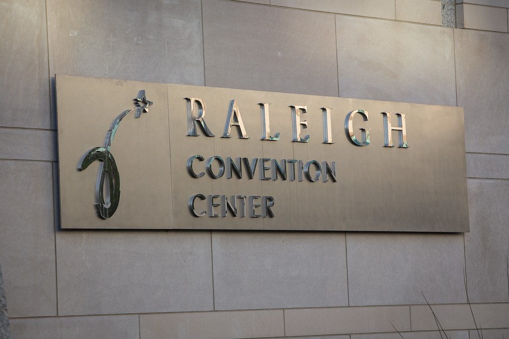 Brushed-metal lettering reading Raleigh Convention Center, with the building logo, mounted on its stone outer wall