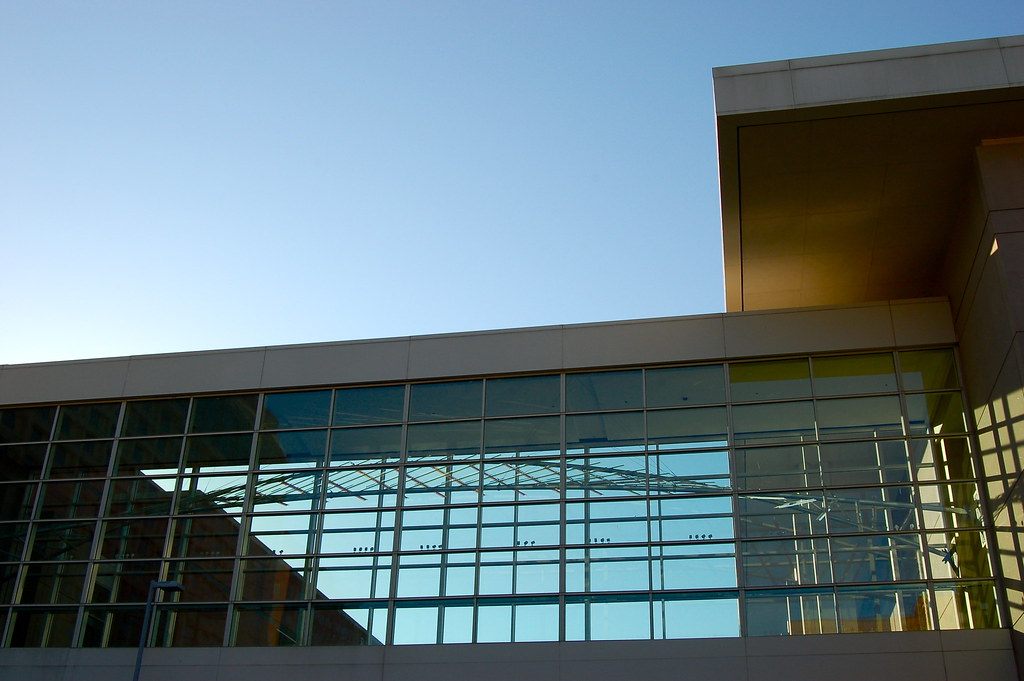 The glass curtain wall and skybridge of the Greater Richmond Convention Center against a clear blue sky