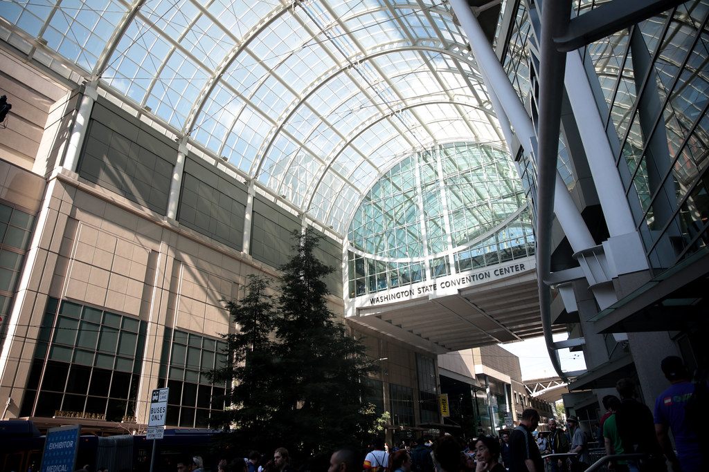The arched glass atrium roof over the Arch building's Pike Street entrance, still signed Washington State Convention Center, with crowds below