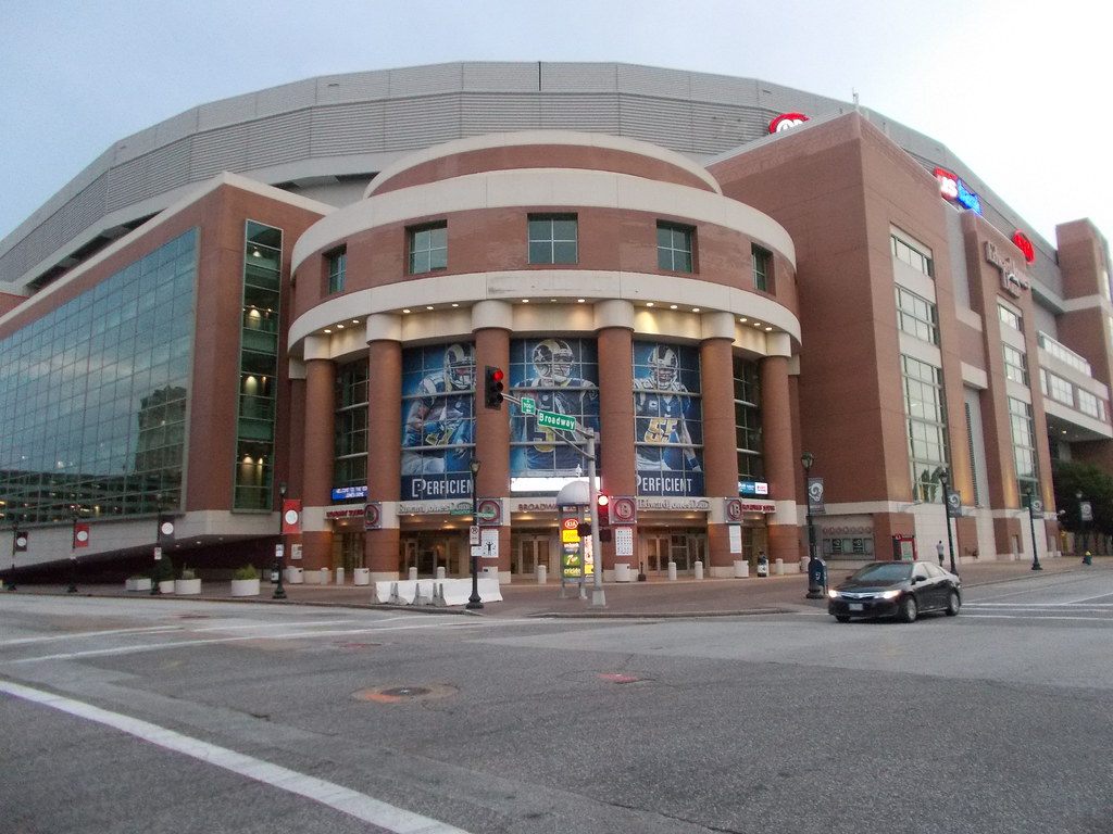The brick rotunda entrance of the Dome on Broadway, with tall glass walls on either side and football banners in the windows