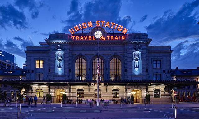 Denver's Union Station illuminated at dusk, with its Travel by Train sign