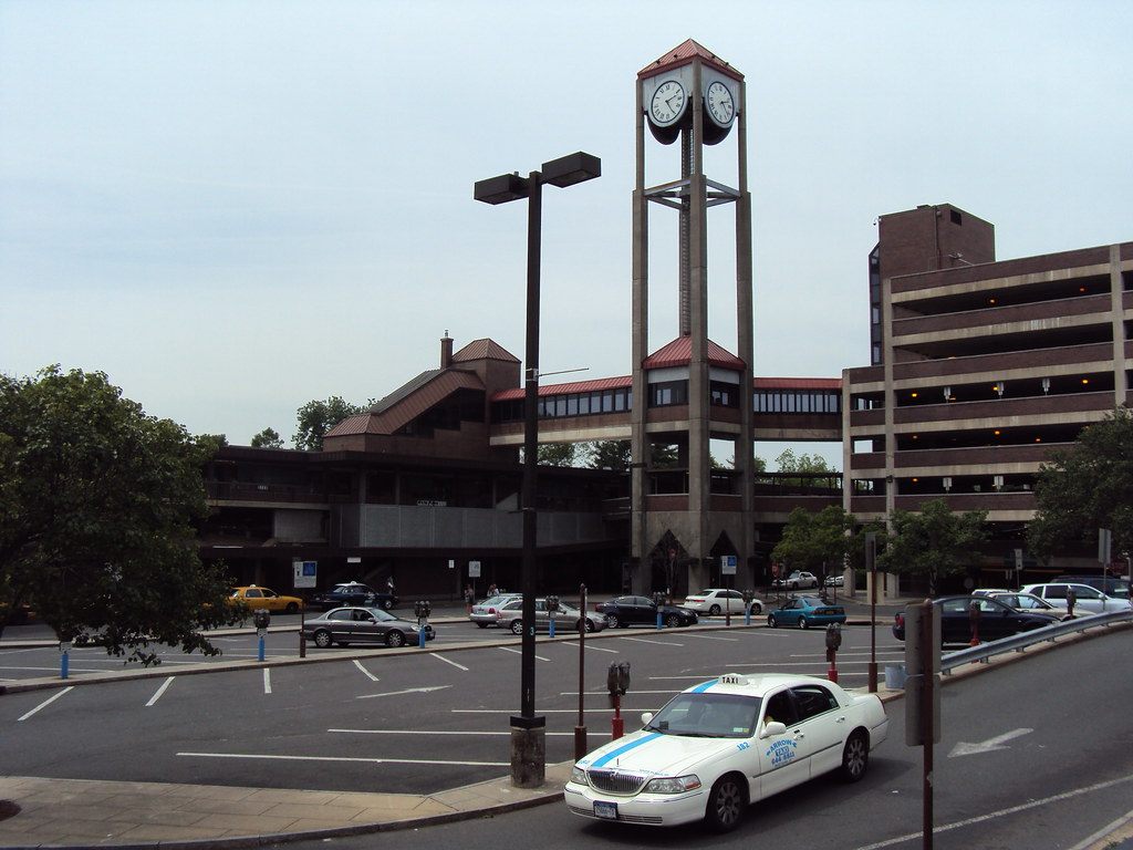 The brick White Plains train station with its clock tower, a parking garage and a taxi in the foreground
