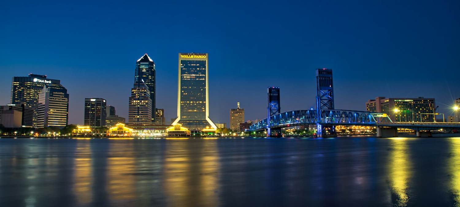 The Jacksonville skyline and the blue-lit Main Street Bridge at twilight across the St. Johns River