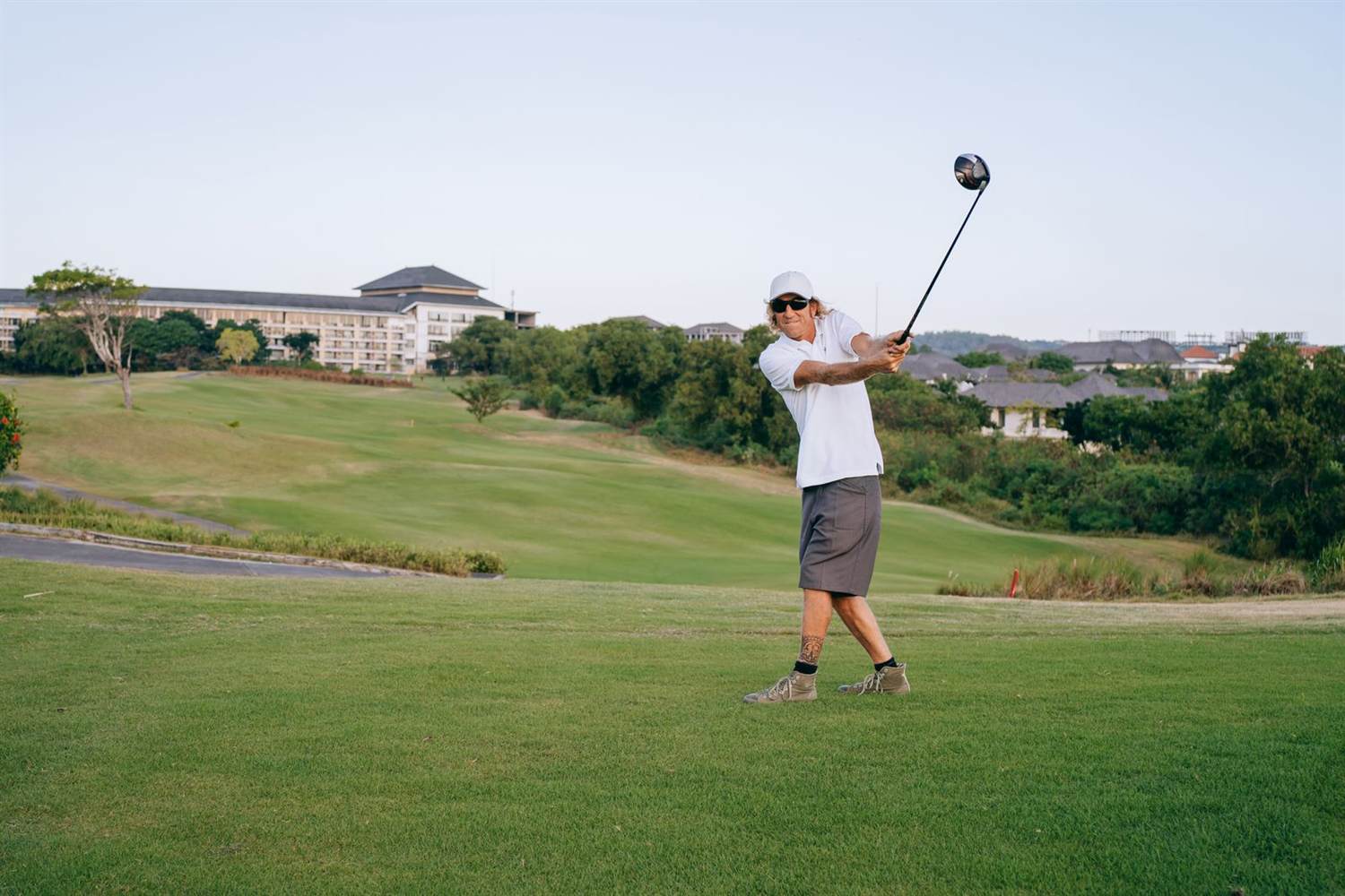 A golfer mid-swing on a green fairway