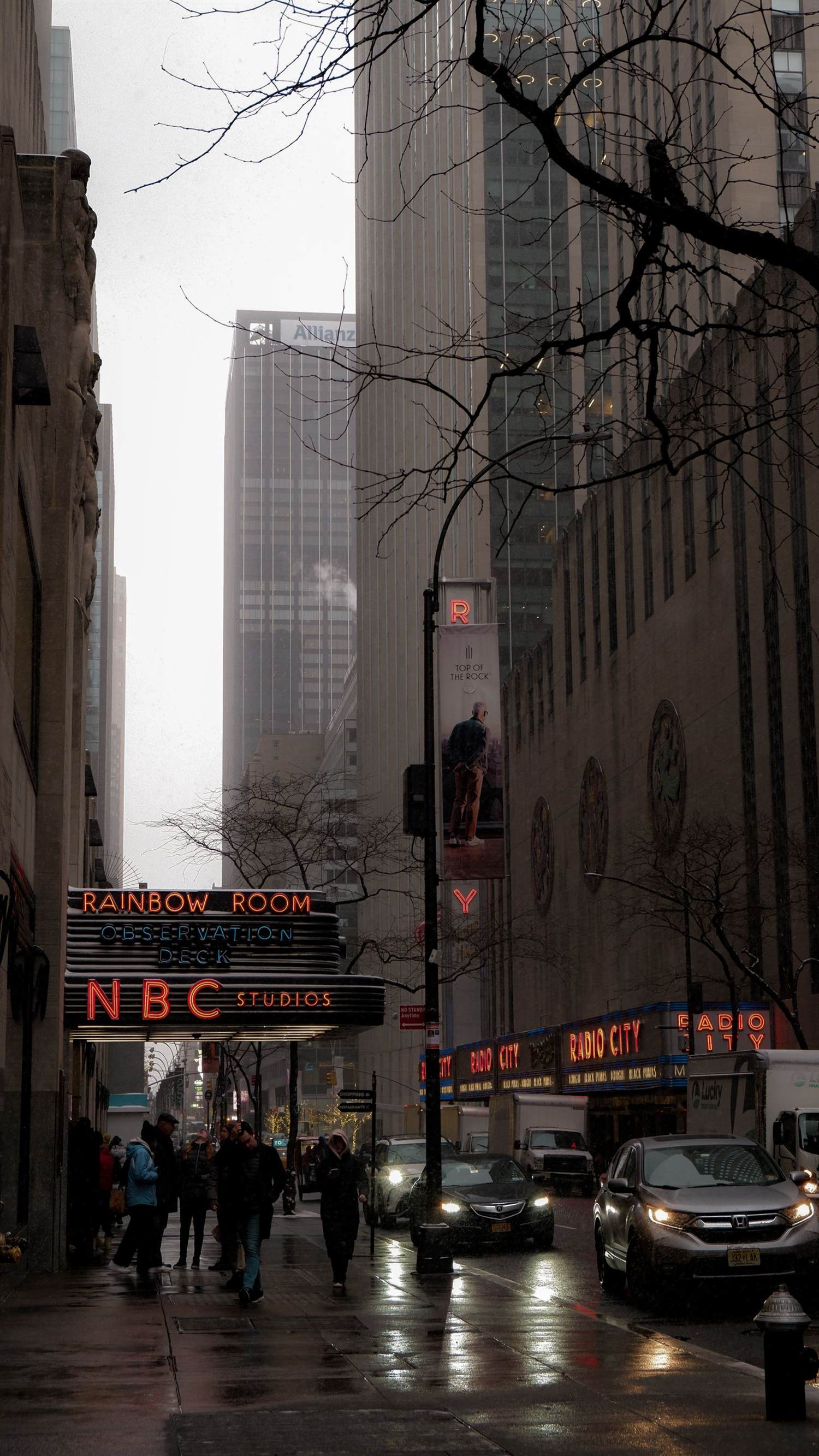 A rainy Sixth Avenue street scene with the NBC Studios and Radio City marquees lit up