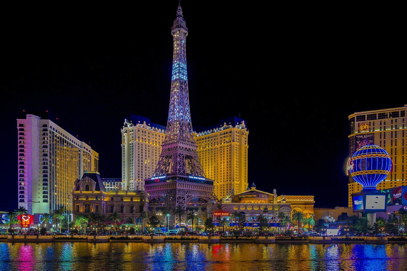Paris Las Vegas and the Eiffel Tower replica lit at night, reflected in the Bellagio lake