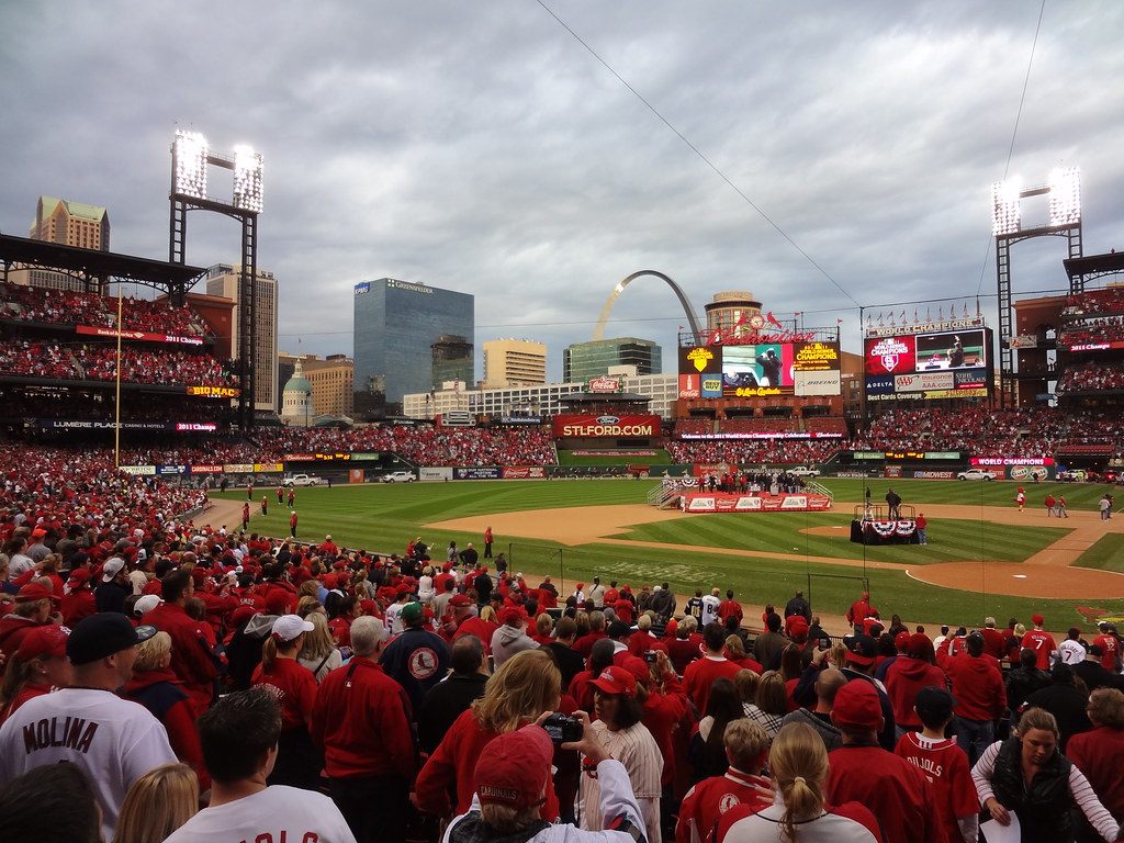 Red-clad Cardinals fans packing Busch Stadium with the Gateway Arch and downtown St. Louis skyline beyond the outfield